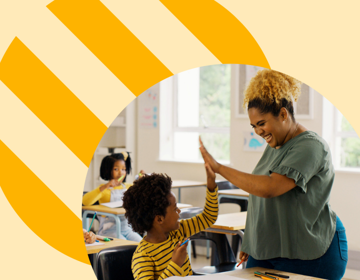 A cheerful medium-dark skin toned teacher giving a high-five to an enthusiastic, dark skin toned, young student in a bright, sunny classroom, with other students in the background, highlighting a positive and supportive educational environment.