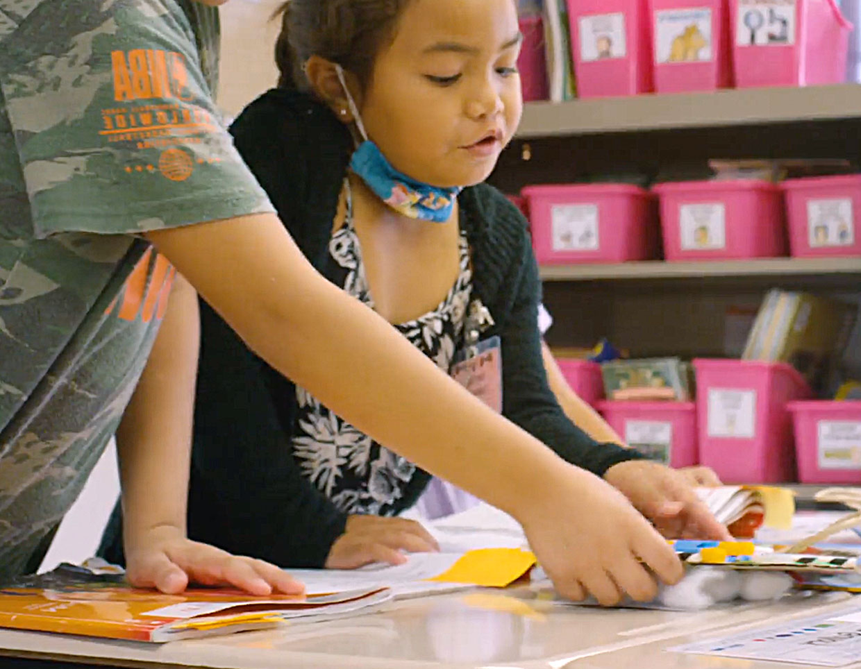 Two young students engaging in a hands-on learning activity at a colorful classroom station.