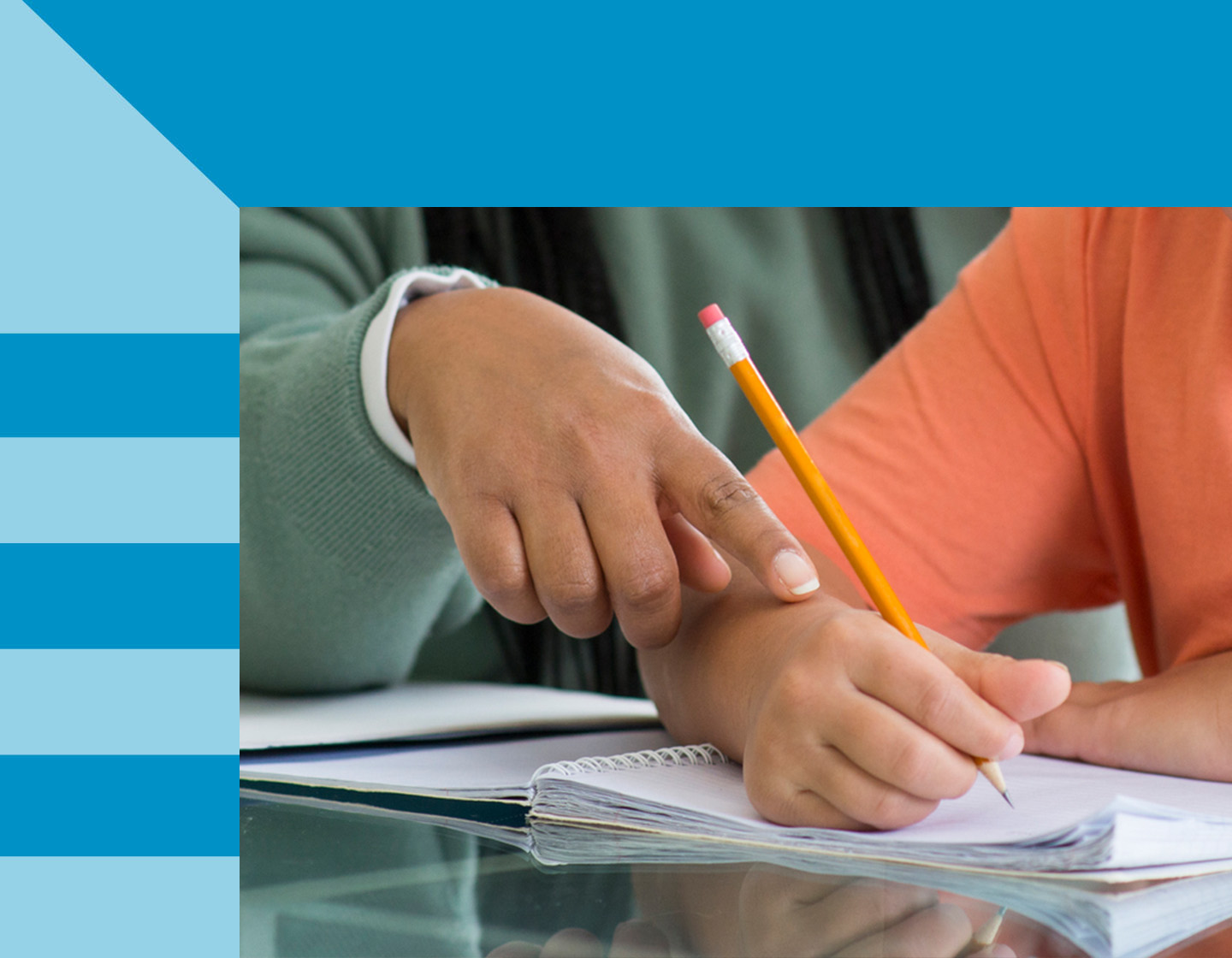 A close-up of two individuals working together on a project, with one guiding the hand of the other, who is writing with a pencil on a notebook, symbolizing guidance, teaching, or collaborative work.