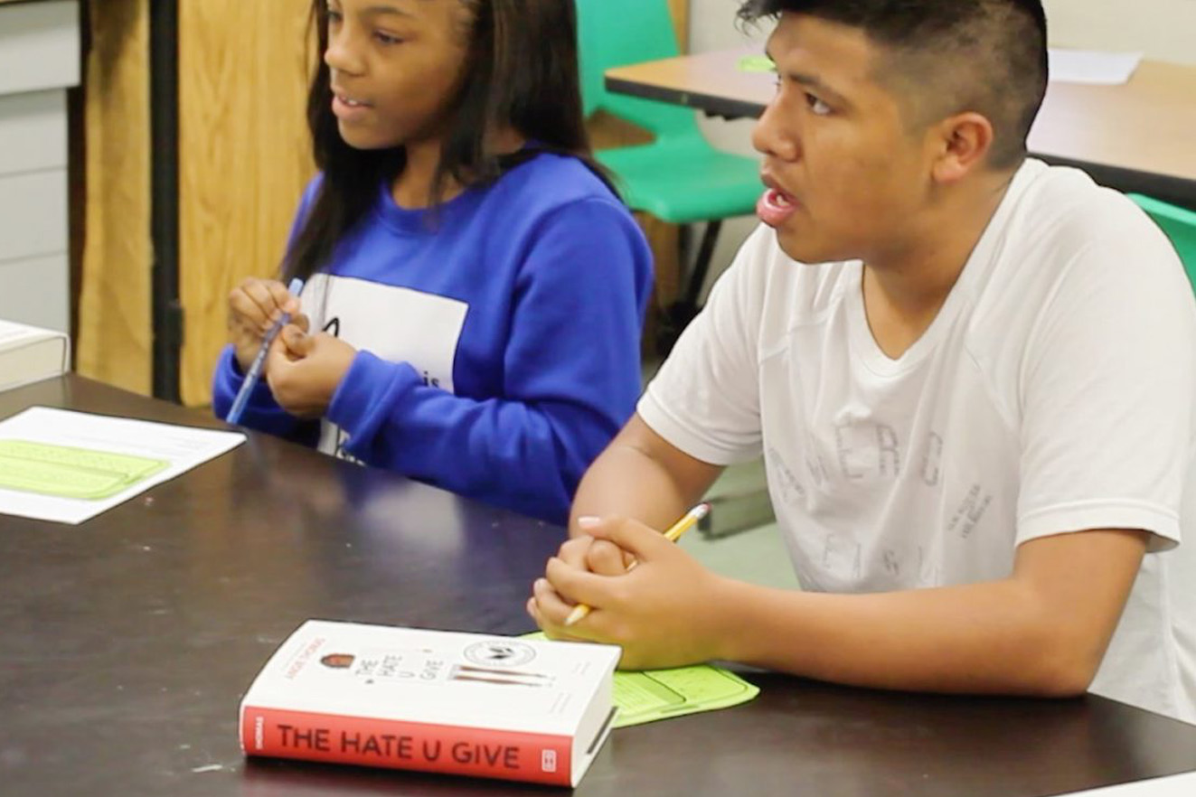 Two students engaged in a classroom discussion with a copy of