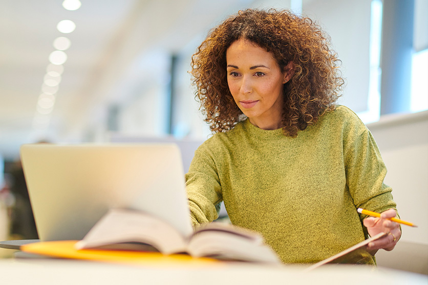 Focused, medium skin toned professional woman engaged in her work at a bright and modern office.